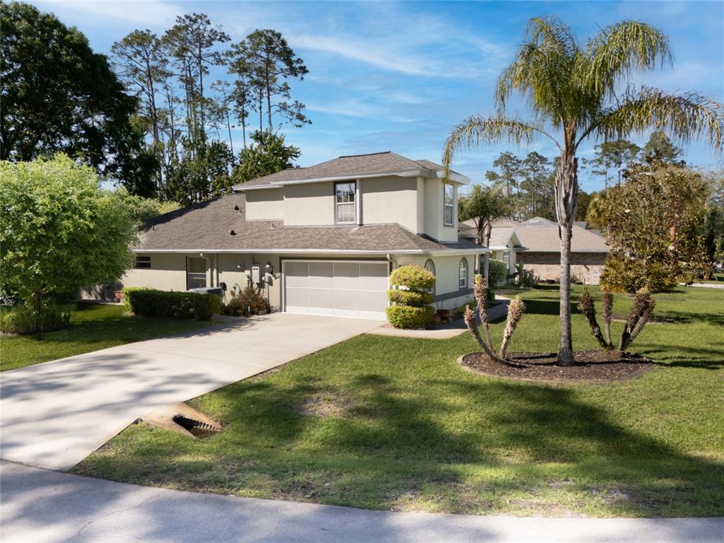 A two-story house with a beige exterior, a two-car garage, and a palm tree — 40 EDGEWATER DRIVE, PALM COAST, FL