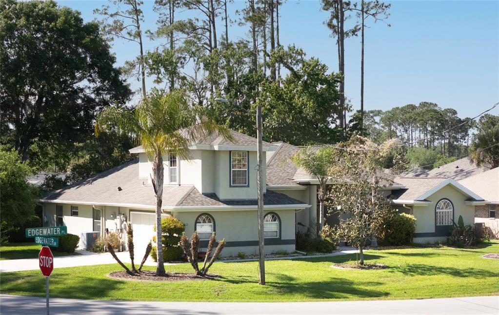 A two-story house with a light-colored exterior, a shingled roof, and a palm tree — 40 EDGEWATER DRIVE, PALM COAST, FL
