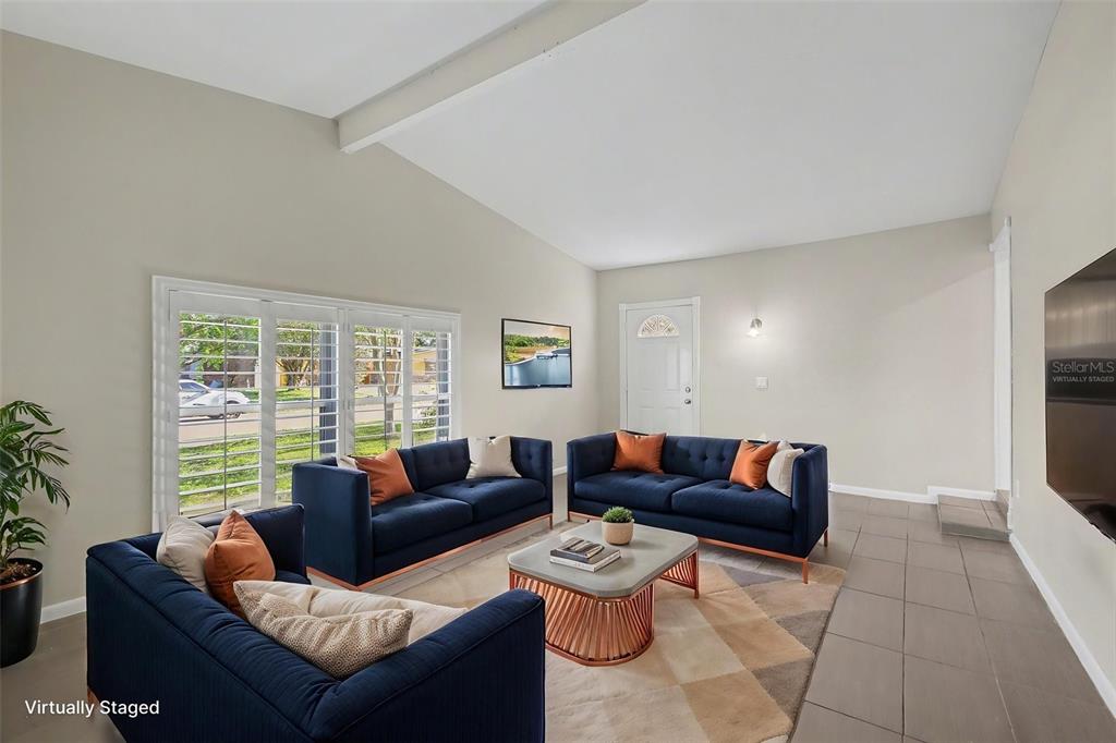 An empty room features light-colored walls, large windows with white shutters, and tiled flooring — 722 GALSWORTHY AVENUE, ORLANDO, FL