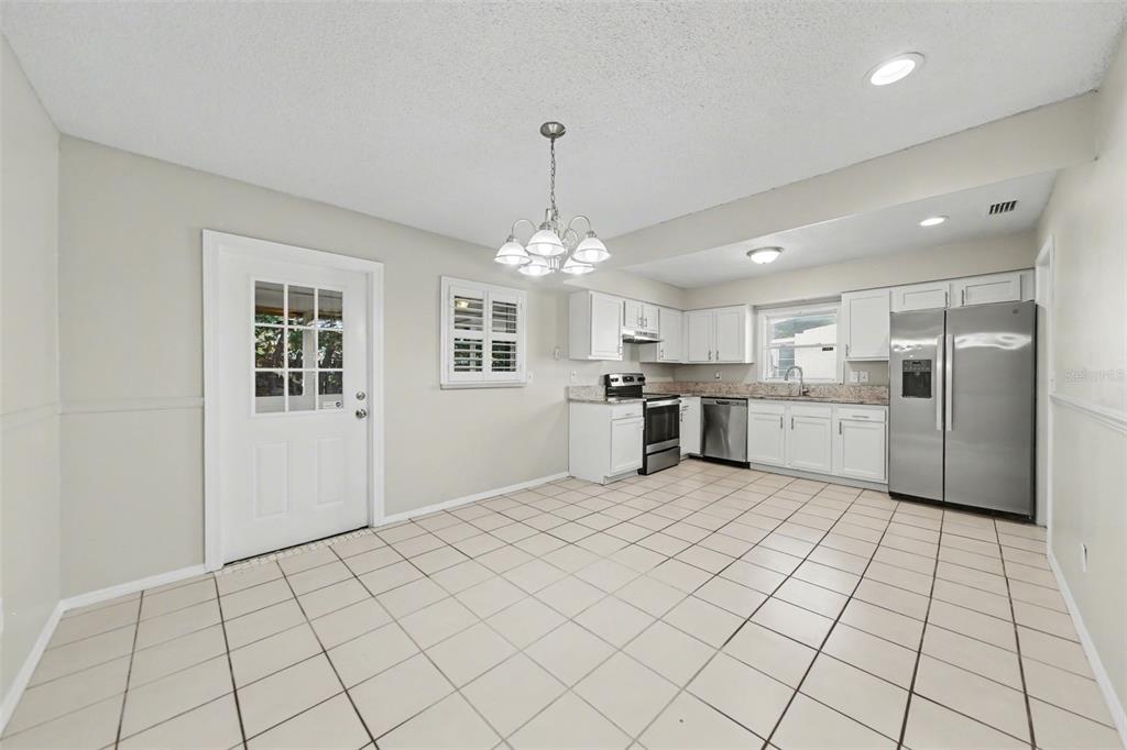 A kitchen with white cabinets, granite countertops, stainless steel appliances, and light-colored tile flooring — 722 GALSWORTHY AVENUE, ORLANDO, FL