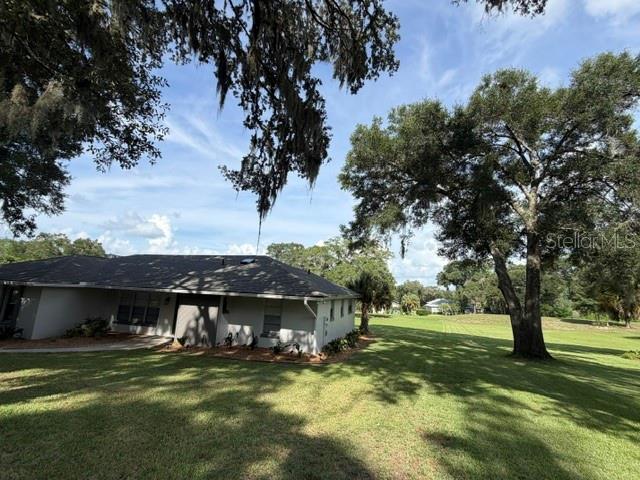 A single-story house with a gray shingled roof, green front door, and a concrete walkway — 8985 SW 196TH TERRACE ROAD, DUNNELLON, FL