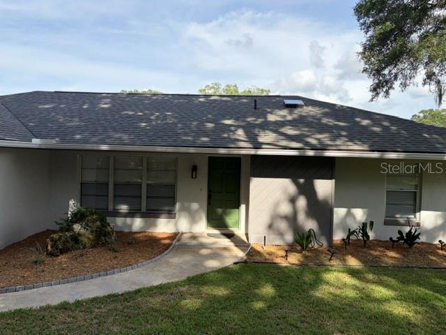 A single-story house with a gray roof sits on a grassy lot with large trees — 8985 SW 196TH TERRACE ROAD, DUNNELLON, FL