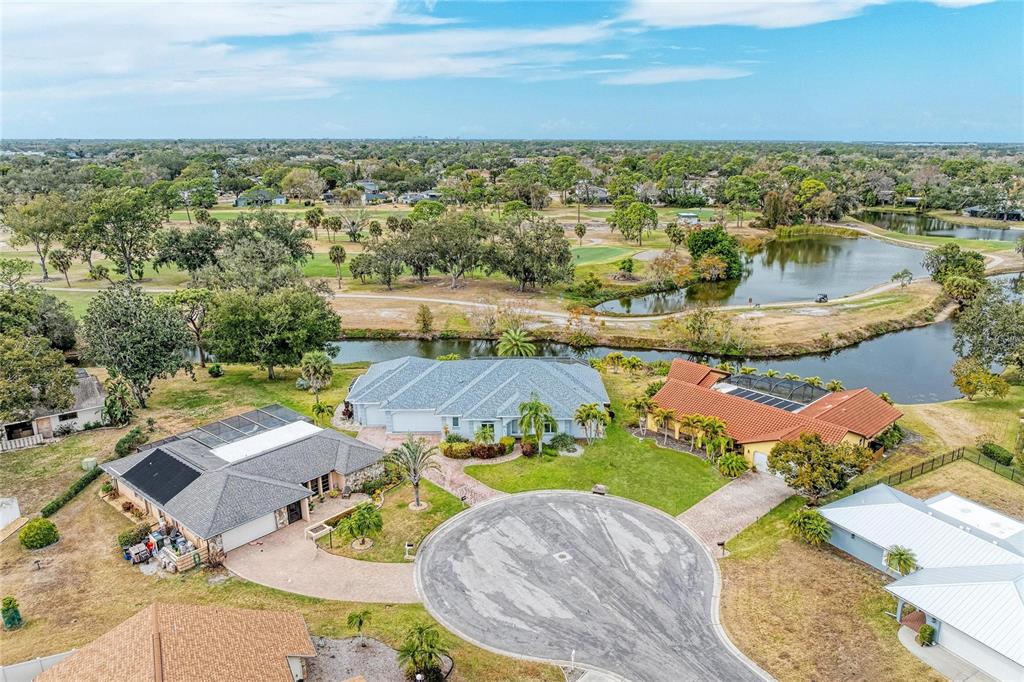 An aerial view shows three houses situated around a cul-de-sac near a pond and golf course — 4540 KIPLING CIRCLE, SARASOTA, FL