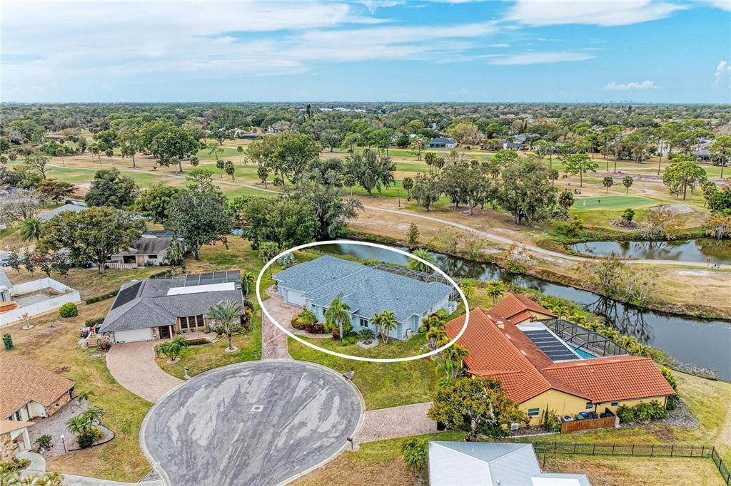 An aerial view shows a single-story house with a grey roof situated near a canal — 4540 KIPLING CIRCLE, SARASOTA, FL
