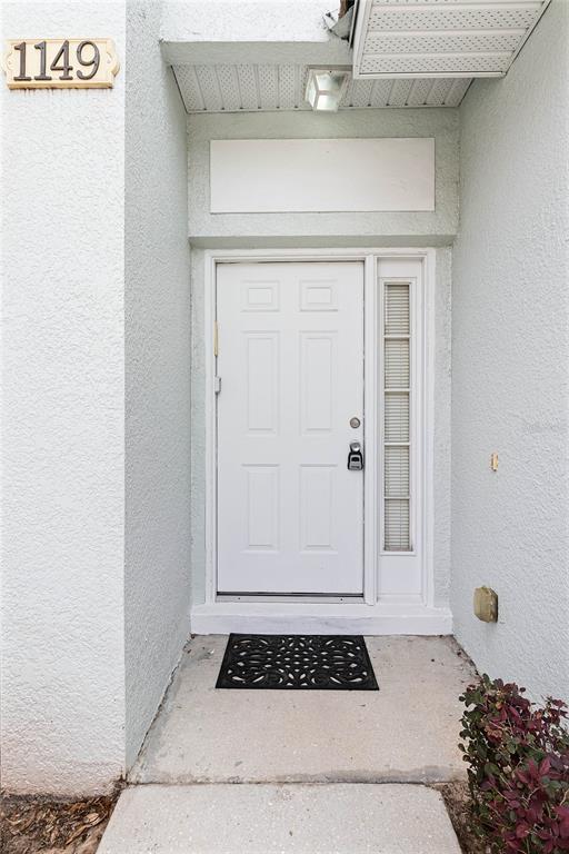 A white front door with a side window and a black mat at the entrance — 1149 S BEACH CIRCLE, KISSIMMEE, FL