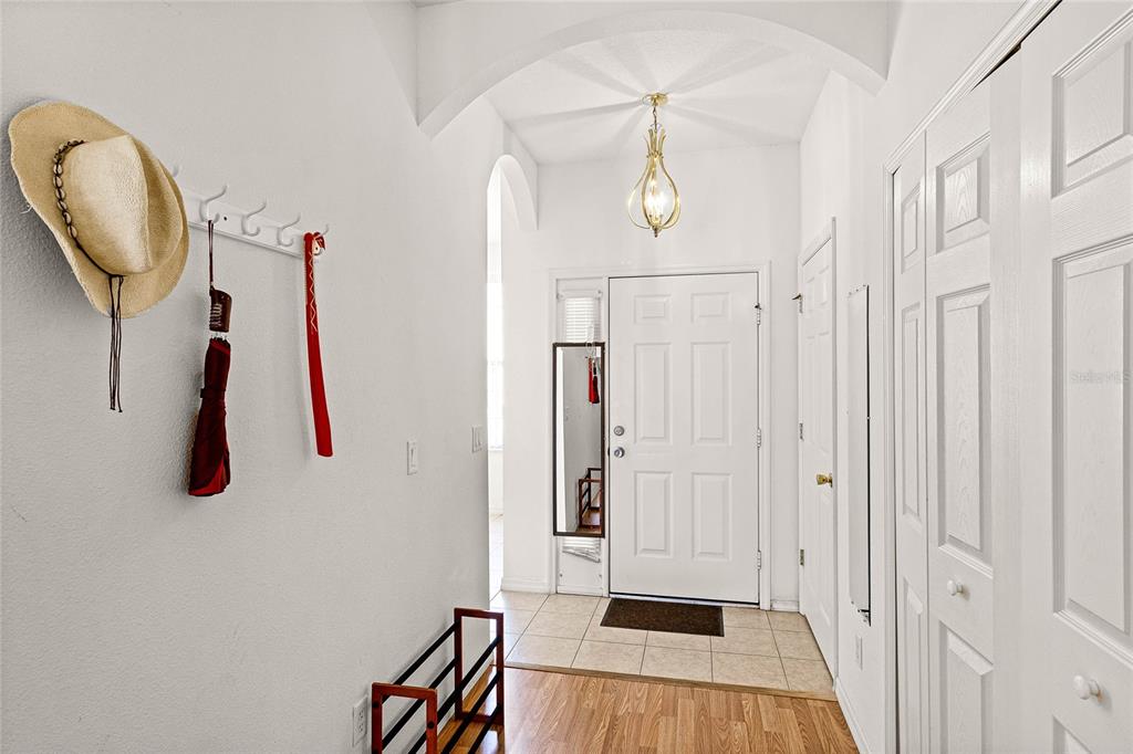 An entryway features a white door, a light fixture, a hat rack, and wood flooring — 1149 S BEACH CIRCLE, KISSIMMEE, FL