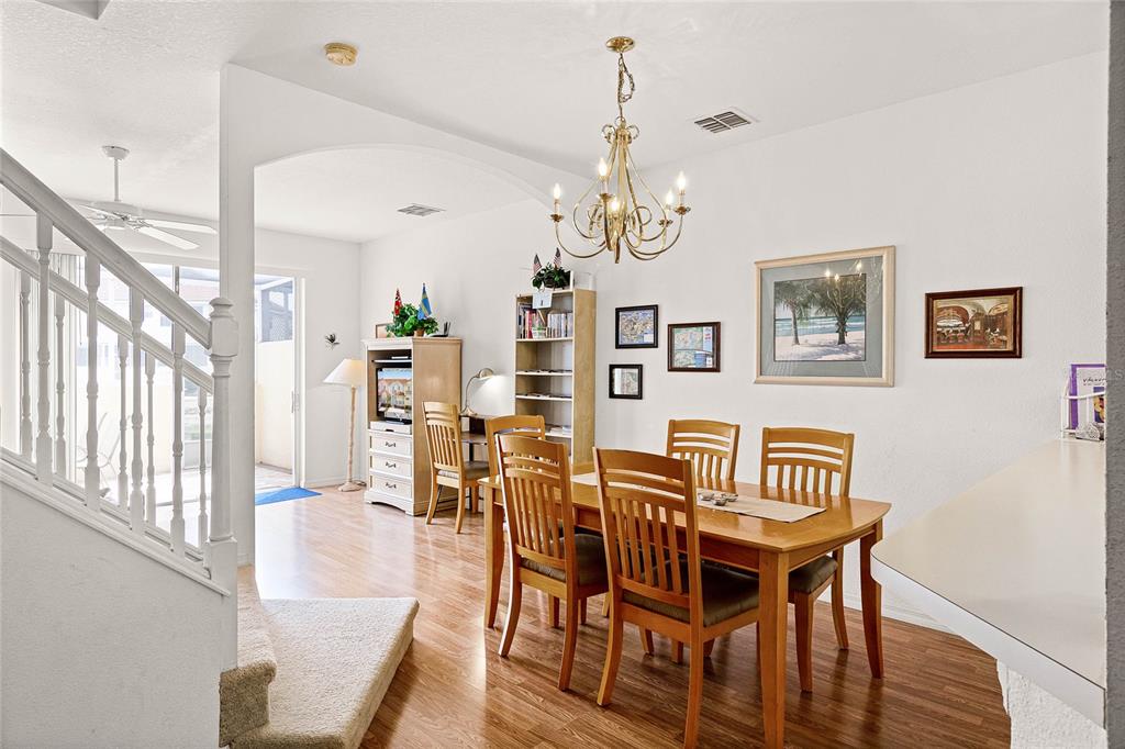 A dining room with a wooden table, chairs, and a chandelier next to a staircase — 1149 S BEACH CIRCLE, KISSIMMEE, FL