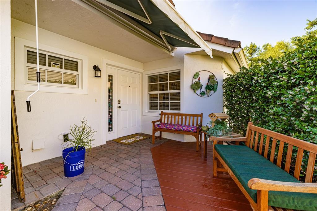 A covered entryway features a brick patio, a wooden deck, two benches, and a white door — 2305 SUMMERSWEET DRIVE, ALVA, FL