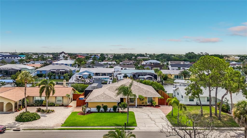 An aerial view shows a yellow single-story house with a driveway and surrounding residential properties — 6517 SOLITAIRE PALM WAY, APOLLO BEACH, FL