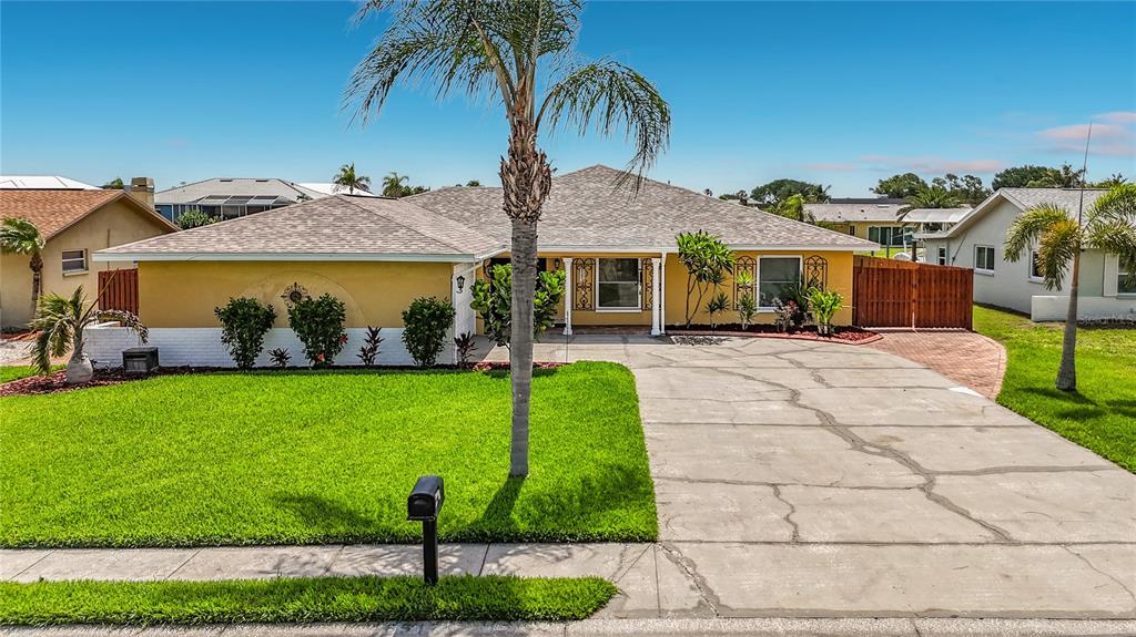A single-story yellow house with a concrete driveway, a palm tree, and a green lawn — 6517 SOLITAIRE PALM WAY, APOLLO BEACH, FL