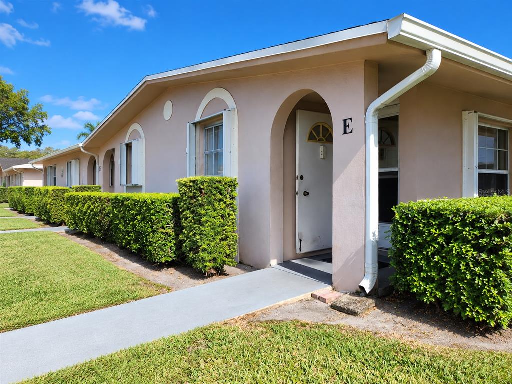 The exterior of a light-colored building features a front entrance marked with the letter E — 2784 DUDLEY DRIVE E UNIT E, WEST PALM BEACH, FL