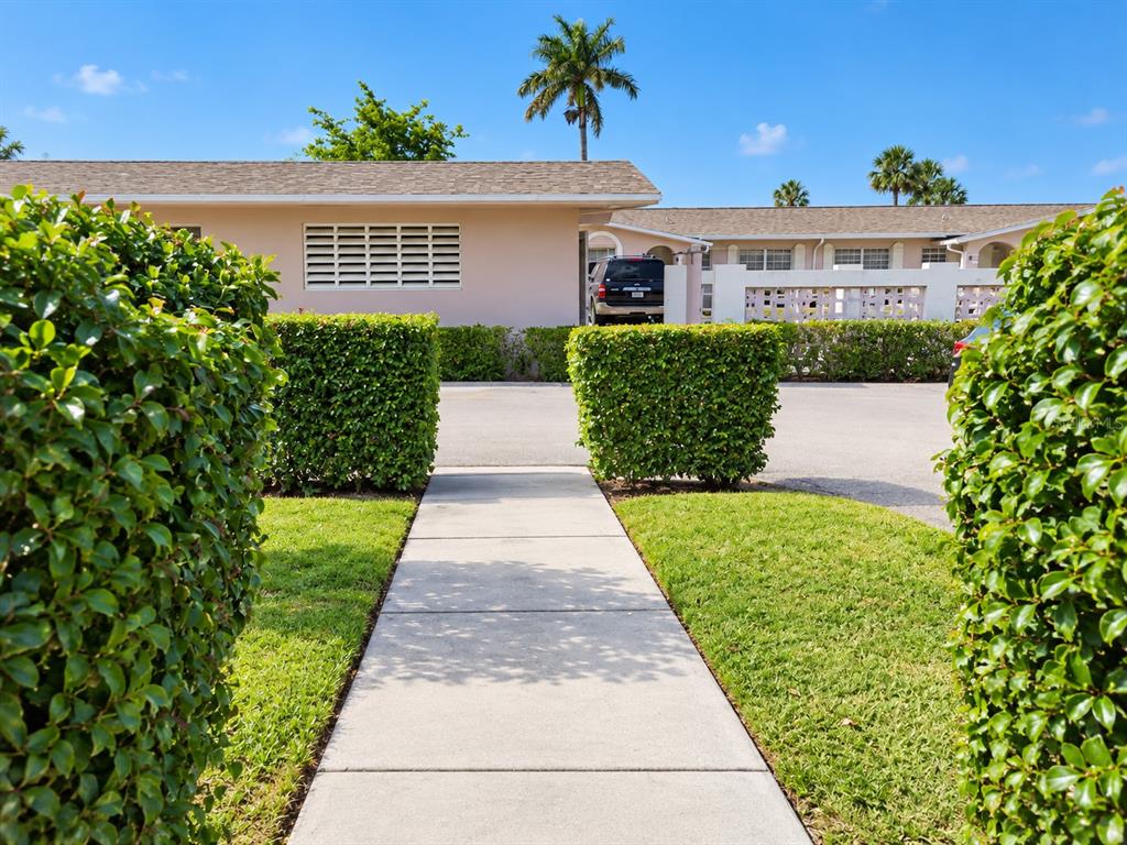 A black metal sign displays the house number 2784 in front of a green hedge — 2784 DUDLEY DRIVE E UNIT E, WEST PALM BEACH, FL