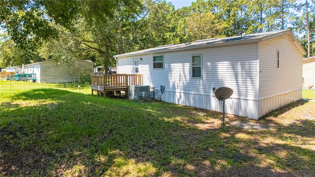 The exterior of a white manufactured home features a small wooden deck and a satellite dish — 8689 ALEXA LANE, JACKSONVILLE, FL