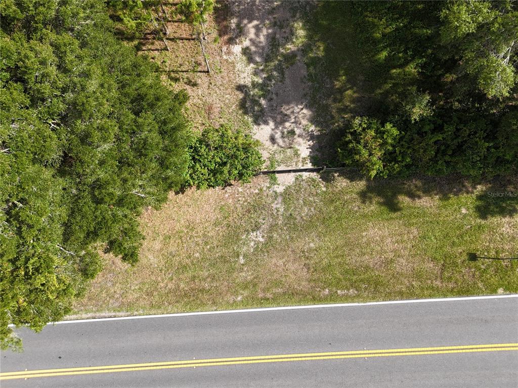 An aerial view shows a grassy lot with trees bordering a paved two-lane road — 00 E COUNTY ROAD 44A, EUSTIS, FL