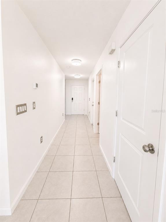 A long, white hallway features light-colored tile flooring and several closed doors — 495 TAFT DRIVE, DAVENPORT, FL