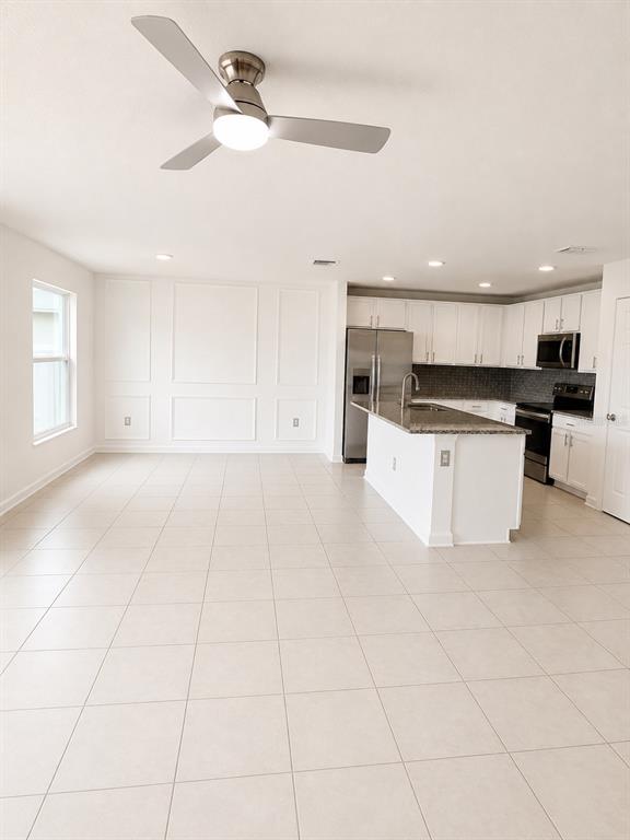 An open-concept kitchen and living area features white cabinetry, granite countertops, and tile flooring — 495 TAFT DRIVE, DAVENPORT, FL