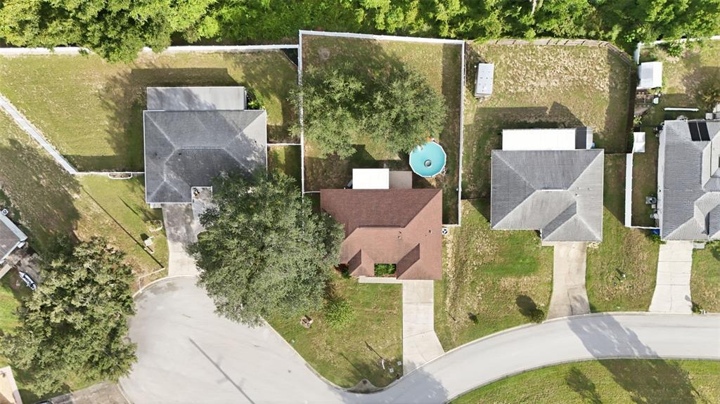 An aerial view shows three suburban houses with driveways, fenced backyards, and mature trees — 236 COUNTRY LAKES CIRCLE, GROVELAND, FL