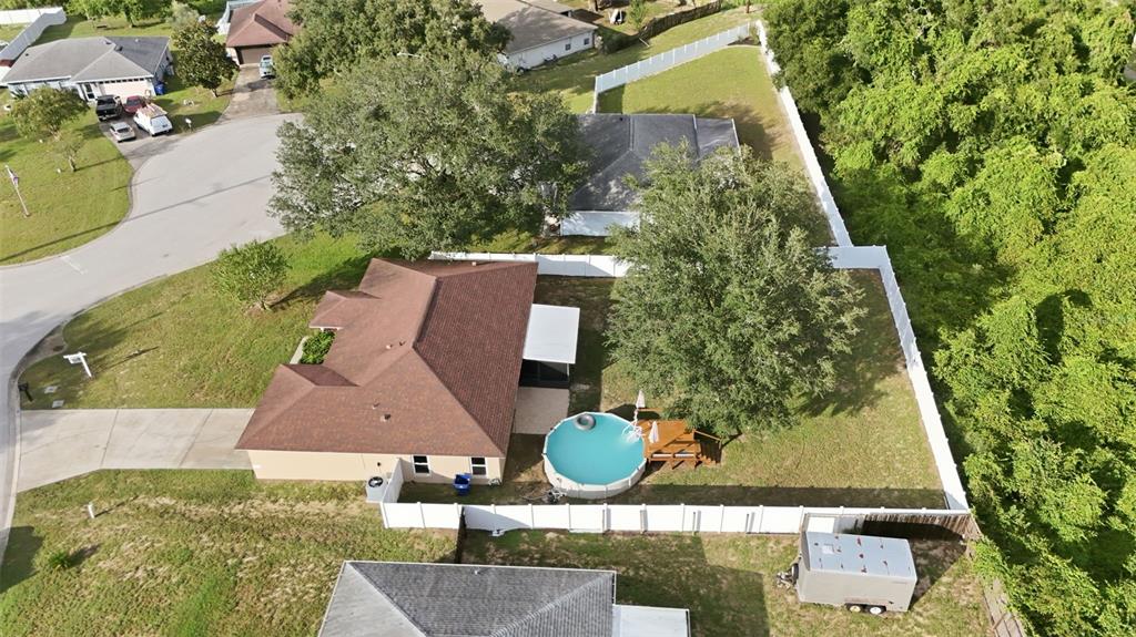 An aerial view shows a house with a brown roof, a backyard pool, and fencing — 236 COUNTRY LAKES CIRCLE, GROVELAND, FL