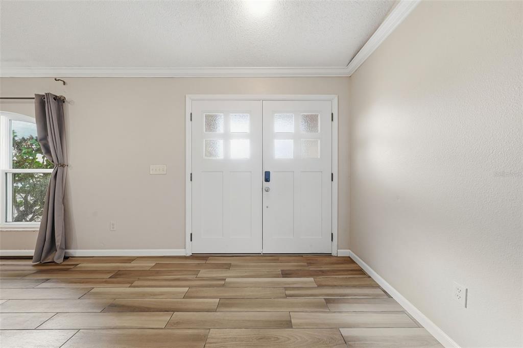 An entryway features white double doors, light-colored walls, and wood-look tile flooring — 236 COUNTRY LAKES CIRCLE, GROVELAND, FL