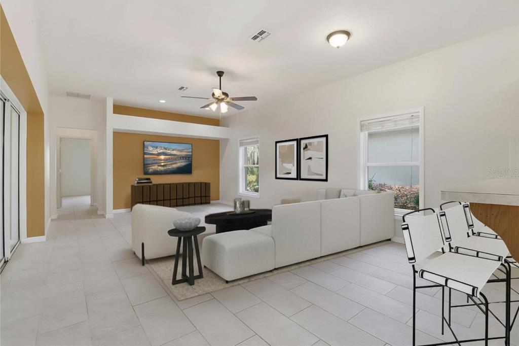 A virtually staged living room with white tile floors, a sectional sofa, and an accent wall — 6301 W GLYNBORNE LOOP, CRYSTAL RIVER, FL