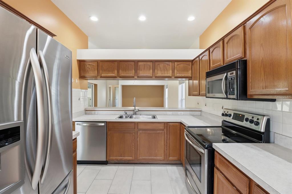 A kitchen with wooden cabinets, stainless steel appliances, white countertops, and light-colored tile flooring — 6301 W GLYNBORNE LOOP, CRYSTAL RIVER, FL