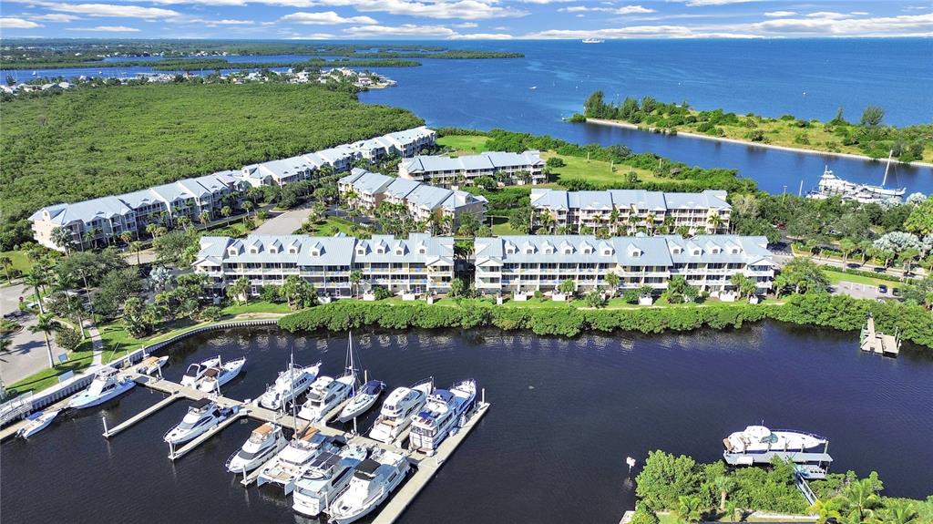An aerial view shows a waterfront condominium complex with a private marina and boats — 423 BAHIA BEACH BOULEVARD, RUSKIN, FL
