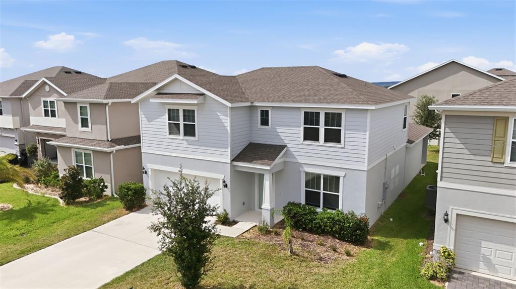 A two-story suburban house with light gray siding, a shingled roof, and a concrete driveway — 14312 CRESTAVISTA AVENUE, CLERMONT, FL