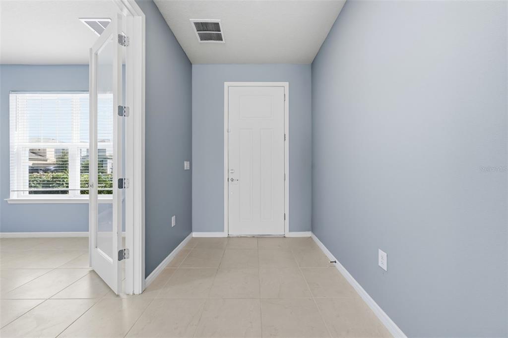 A room with light blue walls, tile flooring, a white door, and glass French doors — 14312 CRESTAVISTA AVENUE, CLERMONT, FL