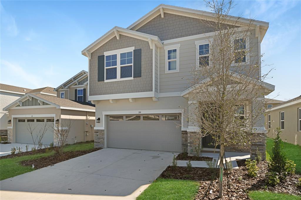 A two-story suburban house features a two-car garage, stone accents, and light-colored siding — 199 BULL FROG LANE, UMATILLA, FL