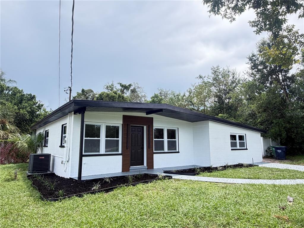 A white single-story house with a dark roof, black trim, and a brown front door — 9505 N WILLOW AVENUE, TAMPA, FL