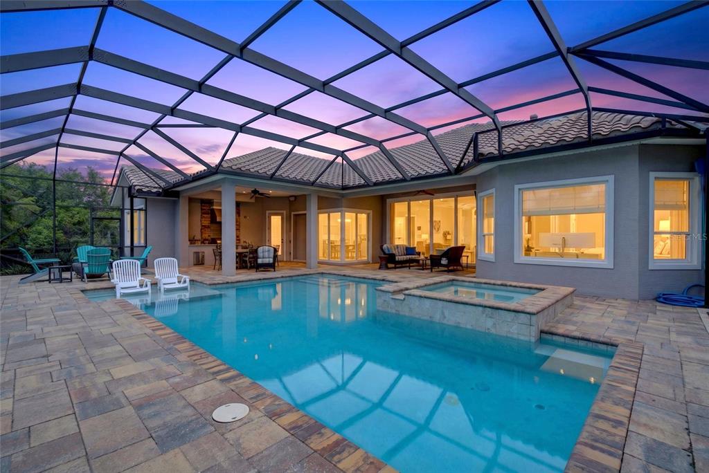 A screened-in patio features a swimming pool, a raised spa, and outdoor seating at dusk — 55 OCEAN OAKS LANE, PALM COAST, FL