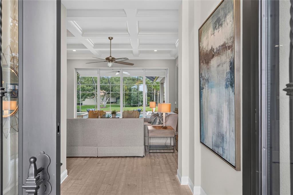 A view from an entryway into a living room with a coffered ceiling and pool view — 55 OCEAN OAKS LANE, PALM COAST, FL