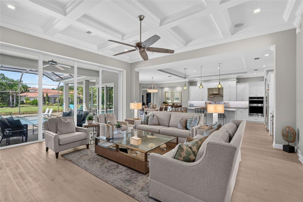 A spacious living room with a coffered ceiling opens to a kitchen and a pool patio — 55 OCEAN OAKS LANE, PALM COAST, FL