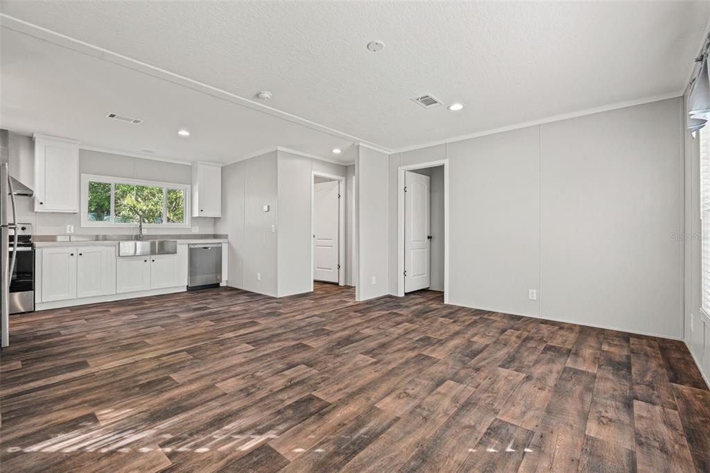 An open-concept kitchen and living area with white cabinets and wood-look flooring — 8432 SWEDEN BOULEVARD, PUNTA GORDA, FL