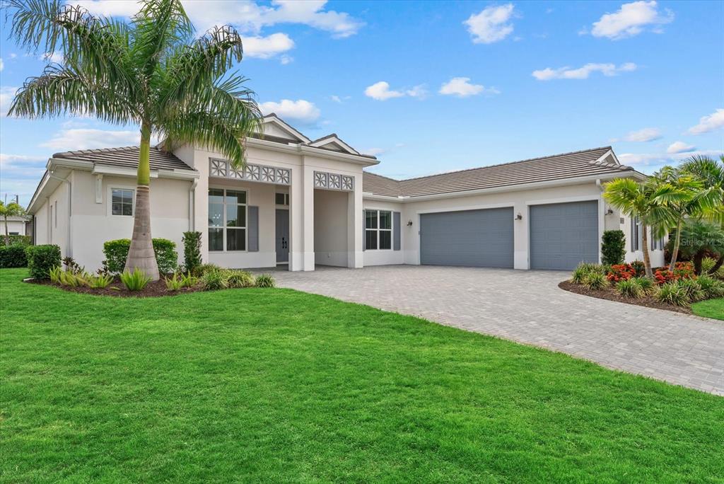 A single-story house with a paved driveway, three-car garage, and a prominent palm tree — 8133 NEVIS RUN, LAKEWOOD RANCH, FL
