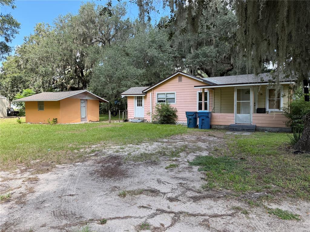 A pink house with a detached orange shed sits on a grassy lot with trees — 815 N ORANGE AVENUE, FORT MEADE, FL