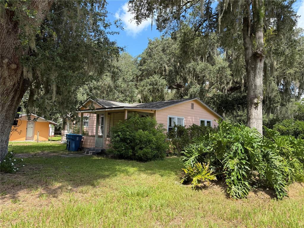 A light pink single-story house sits on a grassy lot shaded by large oak trees — 815 N ORANGE AVENUE, FORT MEADE, FL
