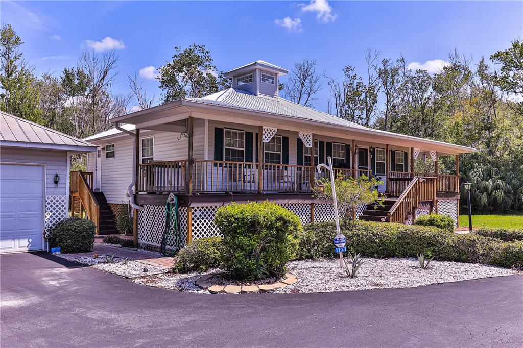 A light-colored house with a metal roof, a wrap-around porch, and a cupola — 11071 W THOREAU PLACE, CRYSTAL RIVER, FL