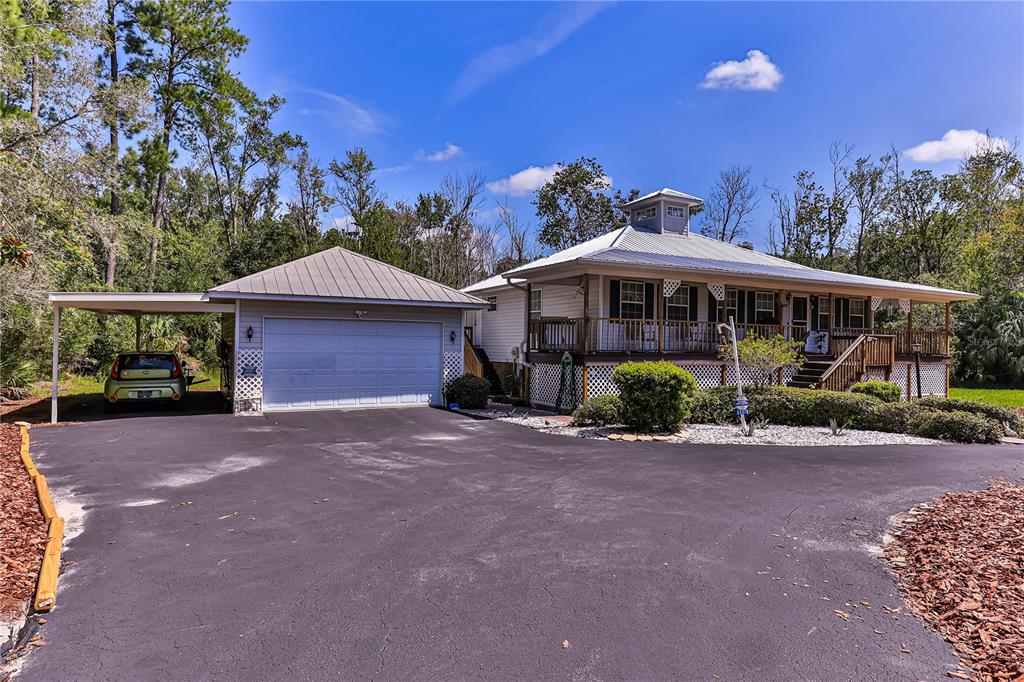 A single-story house with a metal roof, a wrap-around porch, and an attached garage — 11071 W THOREAU PLACE, CRYSTAL RIVER, FL