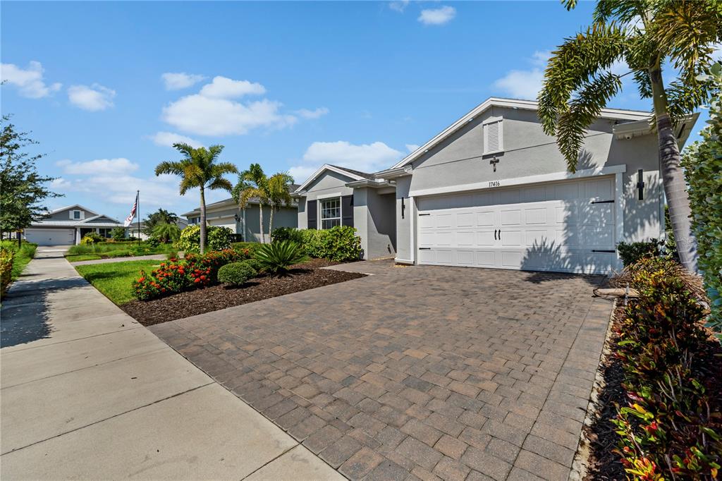 A single-story house features a paved driveway, a two-car garage, and tropical landscaping — 17416 SILVERSPUR DRIVE, PUNTA GORDA, FL