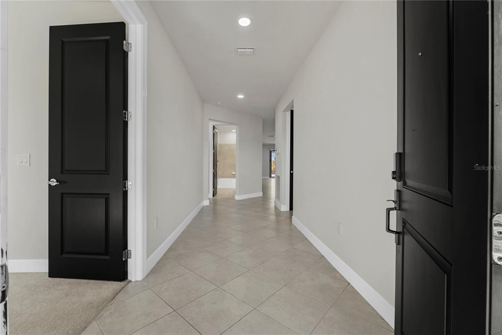 A tiled hallway features light gray walls and several black interior doors — 17416 SILVERSPUR DRIVE, PUNTA GORDA, FL