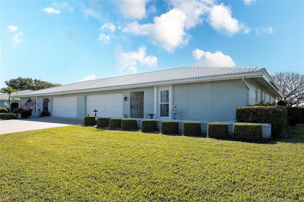A single-story house with a light-colored exterior, a tiled roof, and a manicured lawn — 6517 10TH AVENUE W, BRADENTON, FL