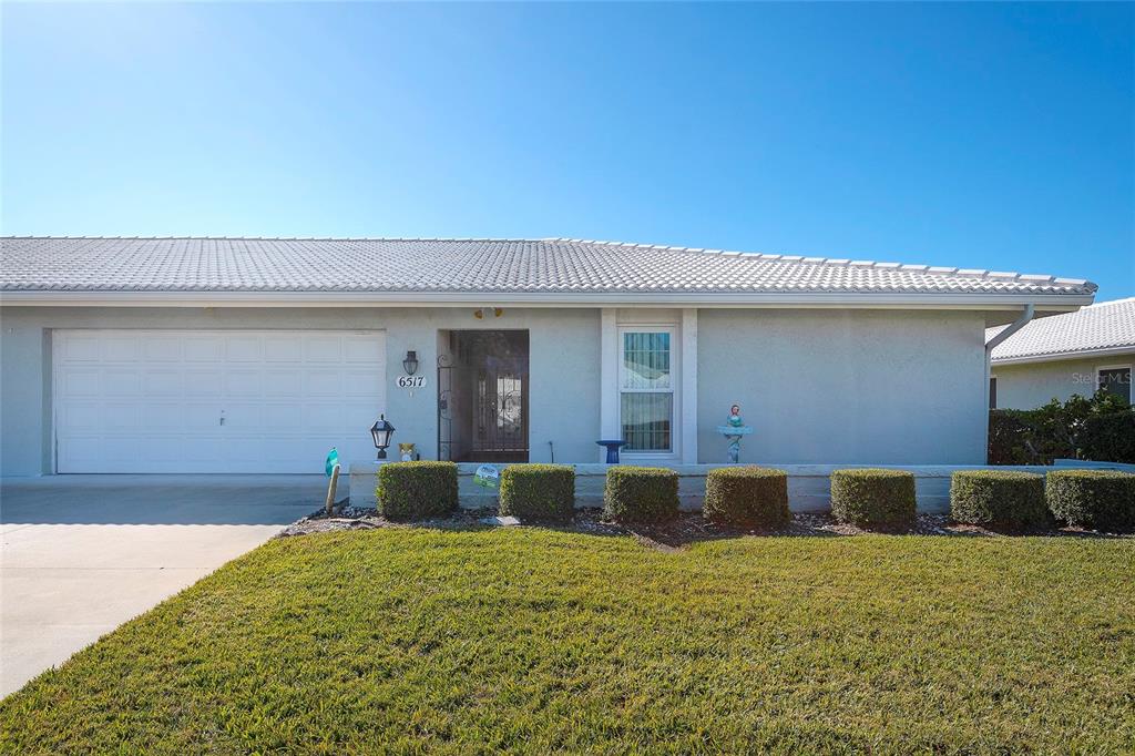 A single-story house with a white garage, a front entrance, and a manicured lawn — 6517 10TH AVENUE W, BRADENTON, FL