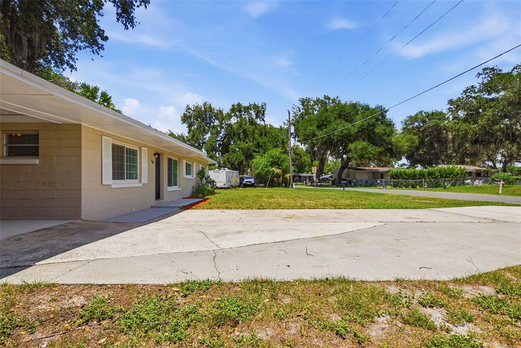 A tan house with a concrete driveway and a carport under a blue sky — 509 SCENIC STREET, LEESBURG, FL