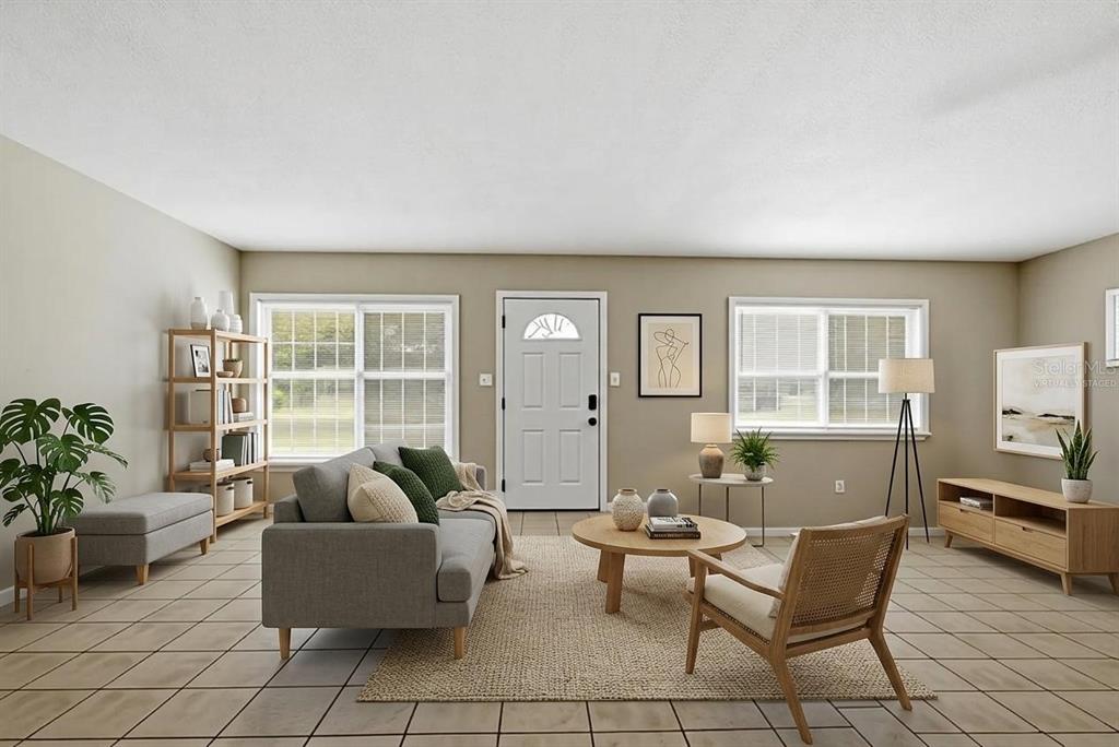 This living room features tile flooring, a gray sofa, a wooden coffee table, and windows — 509 SCENIC STREET, LEESBURG, FL