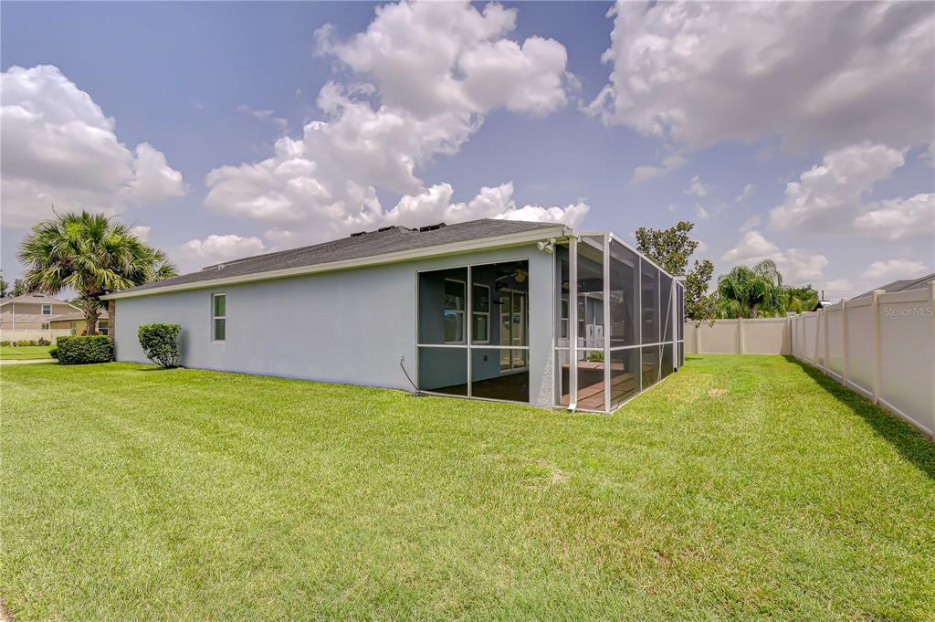 The exterior of a single-story house features a screened-in back porch and a grassy yard — 6622 FAIRWATER DRIVE, RIVERVIEW, FL