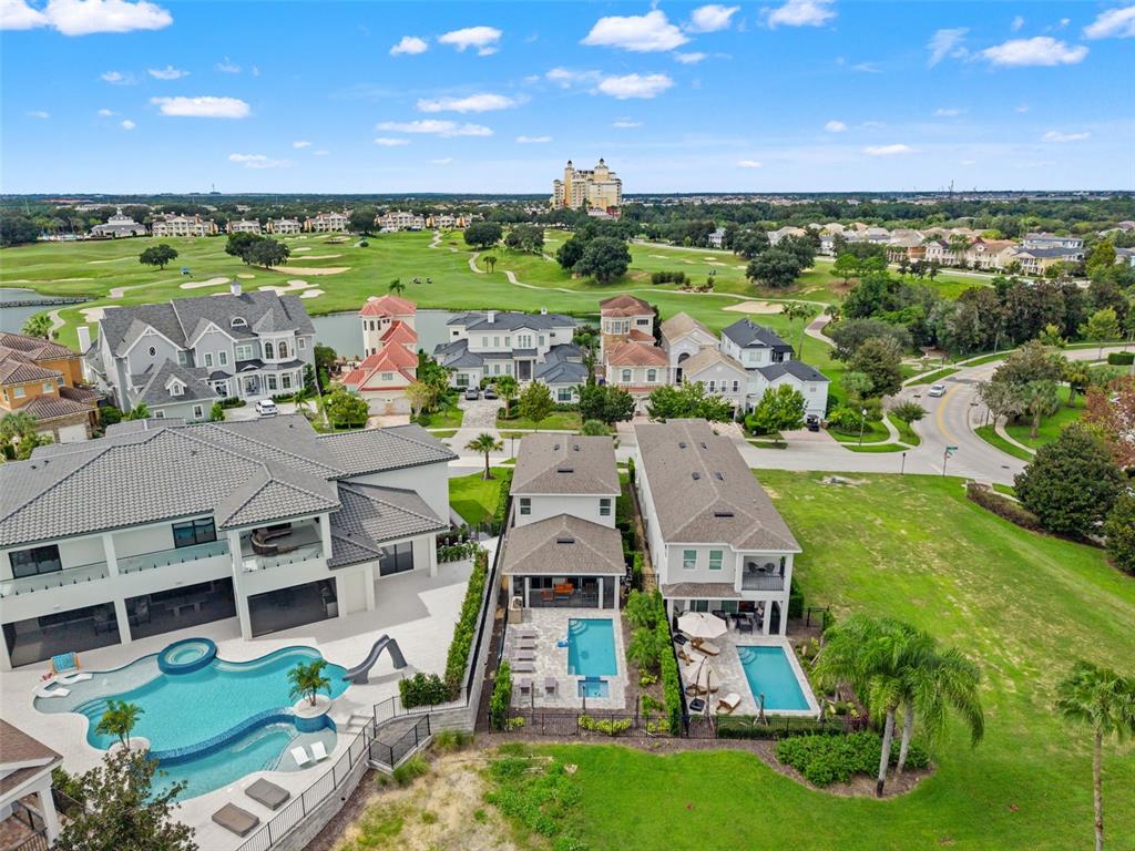 An aerial view shows three large houses with private swimming pools overlooking a golf course — 1407 TITIAN COURT, KISSIMMEE, FL