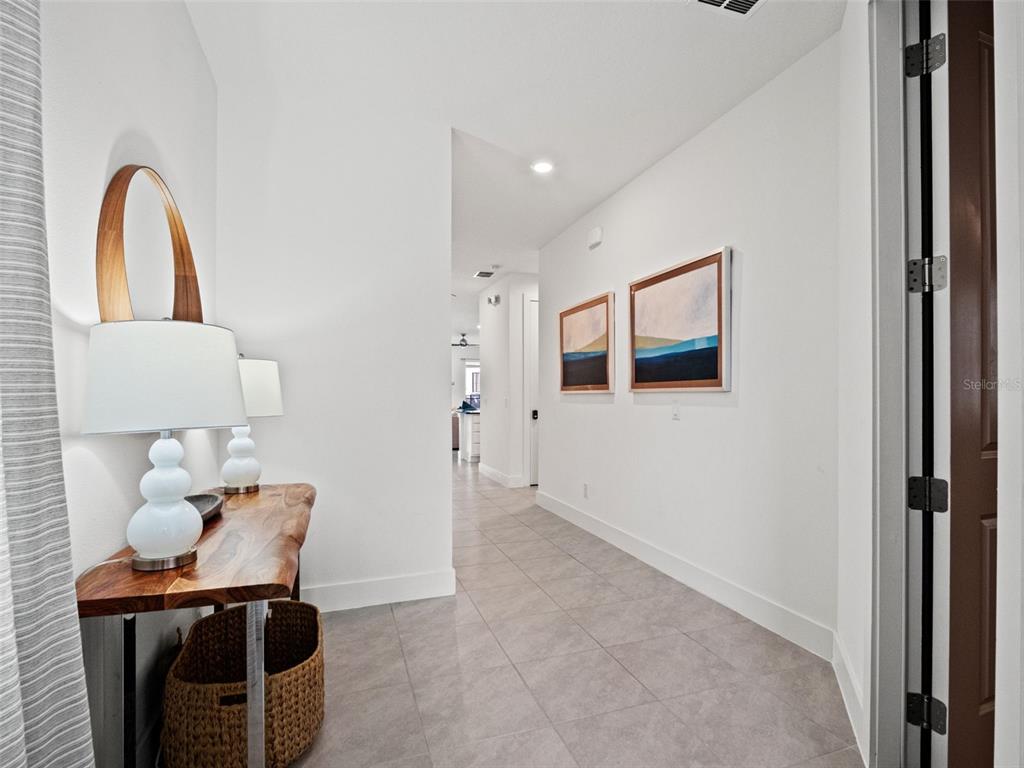 A hallway with tile flooring features a live-edge wood console table and two framed paintings — 1407 TITIAN COURT, KISSIMMEE, FL