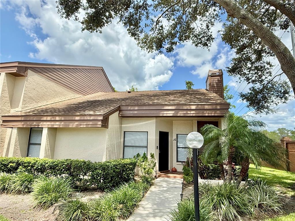 The exterior of a single-story home features a concrete walkway leading to a front entrance — 2816 COUNTRYBROOK DRIVE UNIT L16, PALM HARBOR, FL