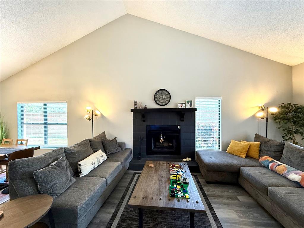 A living room features vaulted ceilings, a wet bar, and gray wood-look flooring — 2816 COUNTRYBROOK DRIVE UNIT L16, PALM HARBOR, FL